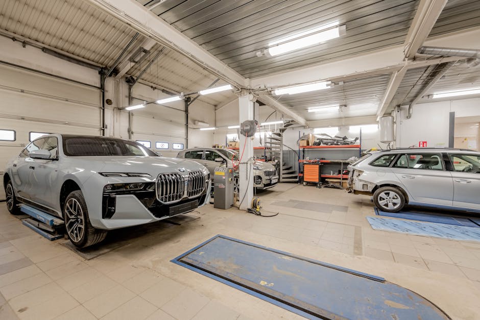 Spacious indoor car garage featuring luxury vehicles under maintenance, showcasing an organized and professional workspace.