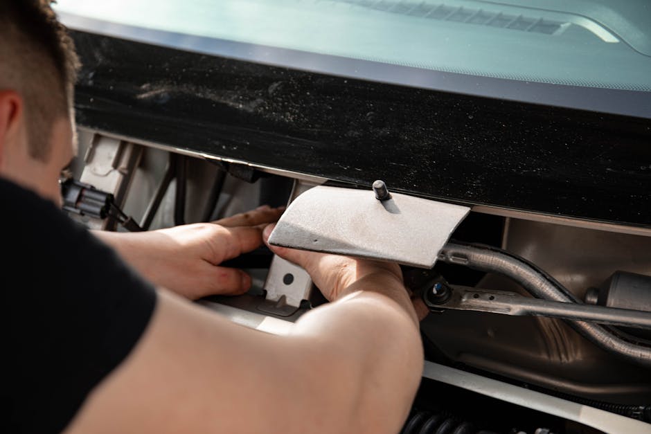 Close-up of a mechanic working on a car engine, focusing on repairs and maintenance.