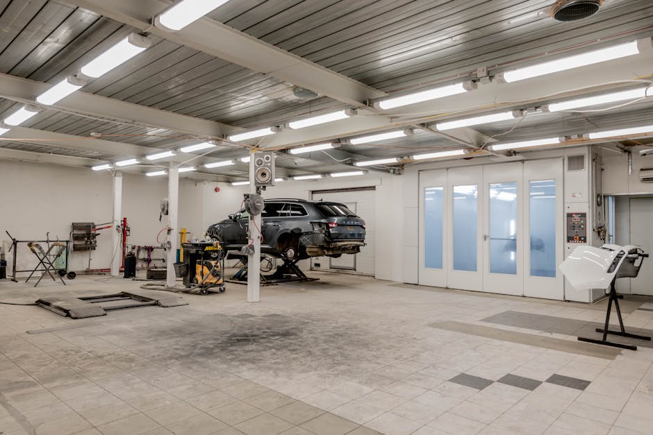 Interior view of a modern car repair garage with vehicle on lift and equipment.