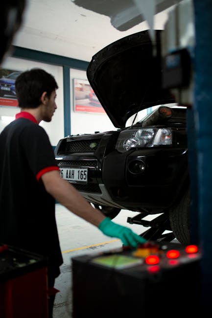 Mechanic using equipment to raise SUV for inspection in an automotive garage.